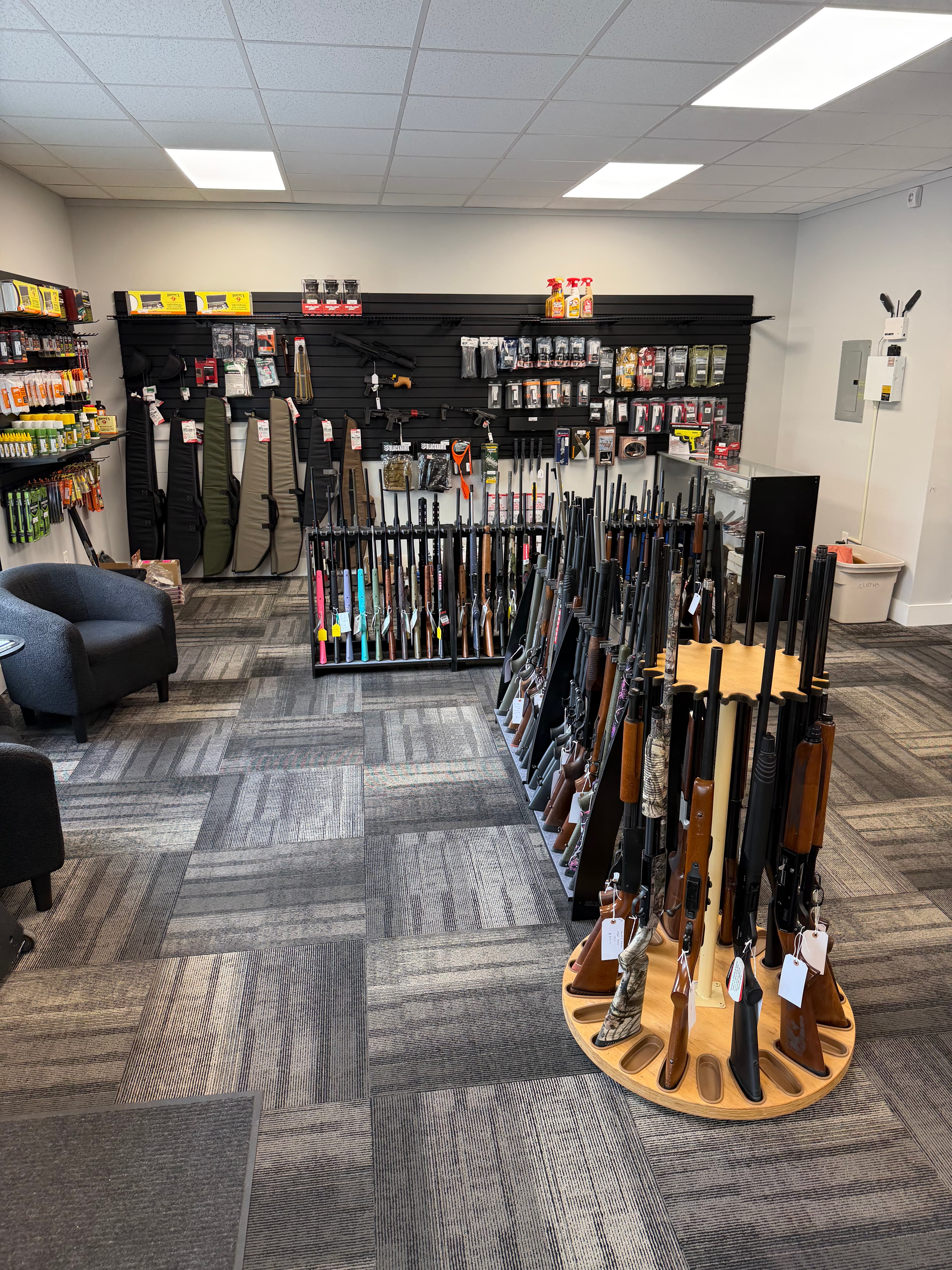 Gun shop interior with rifles and shotguns displayed on circular and wall-mounted racks.